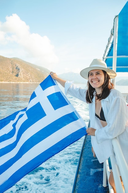 Donna con la bandiera della grecia all'isola di Lefkada in barca da crociera