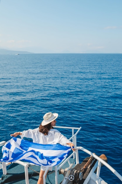 Donna con la bandiera della grecia all'isola di Lefkada in barca da crociera