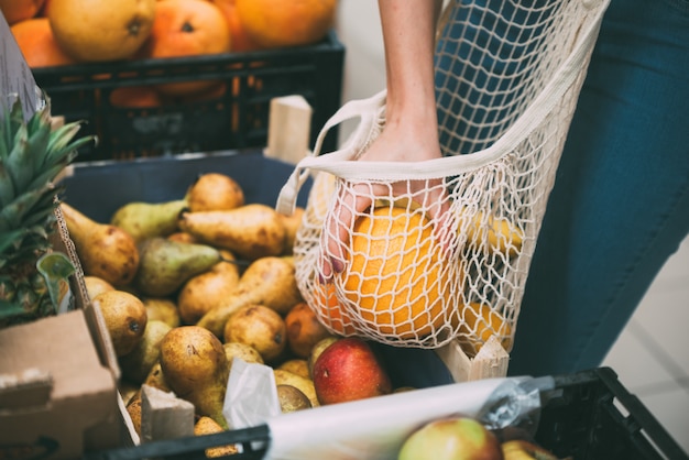 Donna con la borsa della maglia piena di verdure fresche shopping al negozio, zero concetto di rifiuti