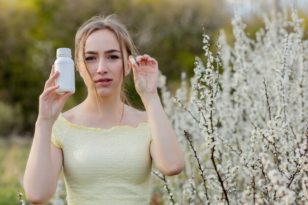 Donna con la medicina nelle mani combattendo le allergie primaverili all'aperto