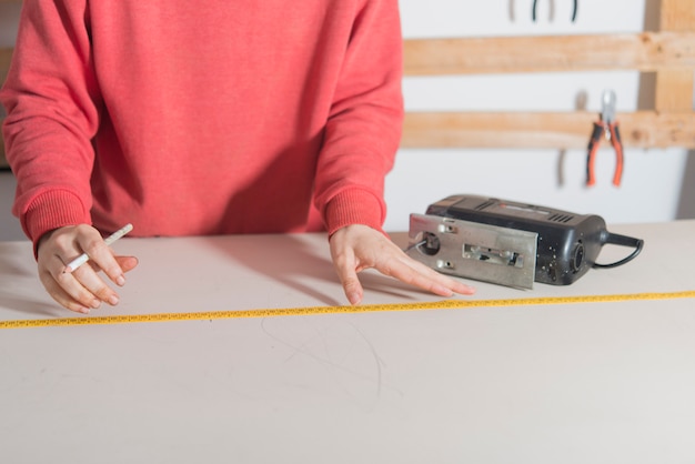 Donna con la misura di nastro pronta a tagliare un legno