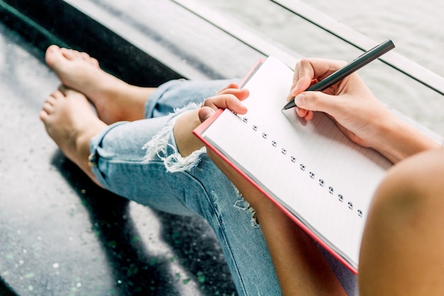 Donna con la penna che scrive su un taccuino che si siede a casa