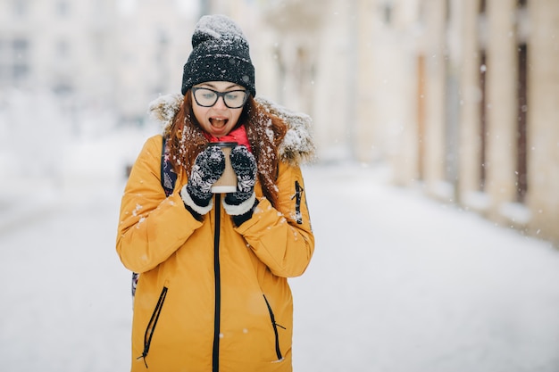 Donna con la tazza di tè o caffè nella città di inverno