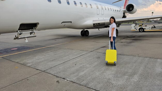 Donna con la valigia in piedi davanti all'aereo