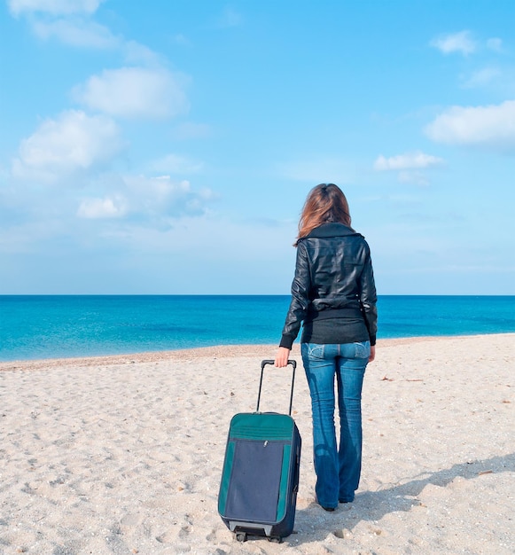 Donna con la valigia su una spiaggia deserta