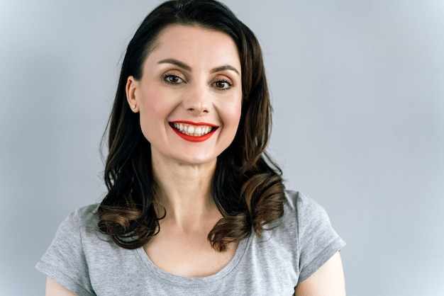 Donna con labbra rosse e un ampio sorriso in posa in studio.