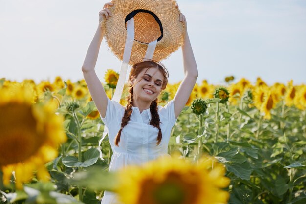 Donna con le trecce in un cappello di paglia in un vestito bianco un campo di girasoli agricoltura ora legale