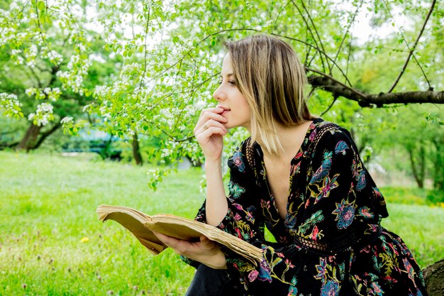 donna con libro nel parco di primavera.