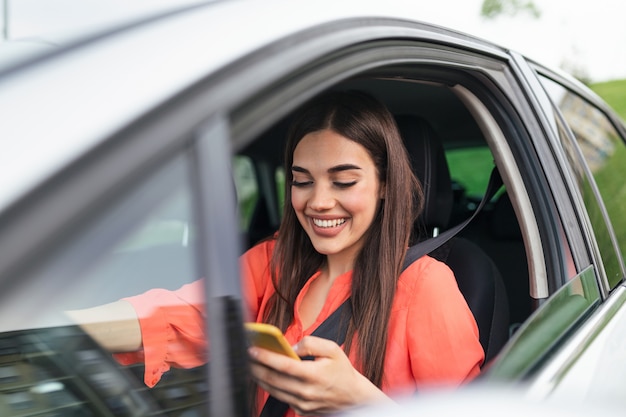 Donna con lo smartphone nella sua auto. La ragazza sta usando uno smartphone