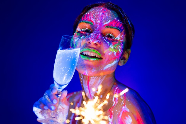 Donna con lo sparkler e bicchiere di champagne alla luce al neon. Concetto di vacanze e Capodanno