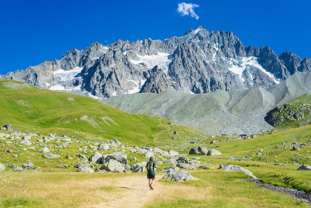 Donna con lo zaino che fa un'escursione verso la cima della montagna, il ghiacciaio panoramico e il paesaggio estivo spettacolare