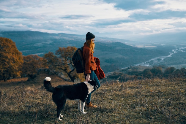 Donna con lo zaino sulla natura accanto al paesaggio montano a piedi del cane