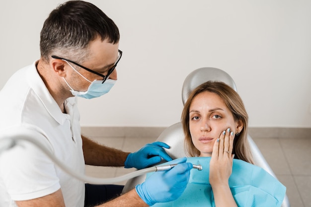 Donna con mal di denti in consultazione e trattamento presso il dentista in stomatologia Il dentista tratta i denti della carie per la ragazza