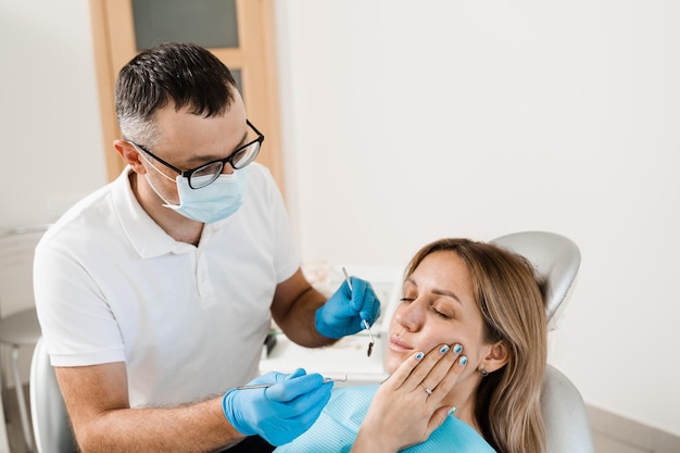 Donna con mal di denti in consultazione e trattamento presso il dentista in stomatologia Il dentista tratta i denti della carie per la ragazza