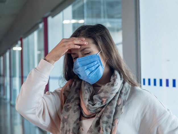 Donna con mal di testa, indossando la maschera medica