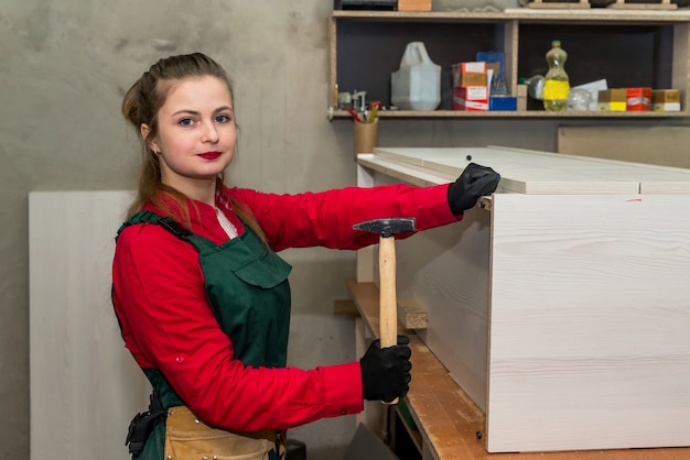 Donna con martello che costruisce mobili in falegnameria