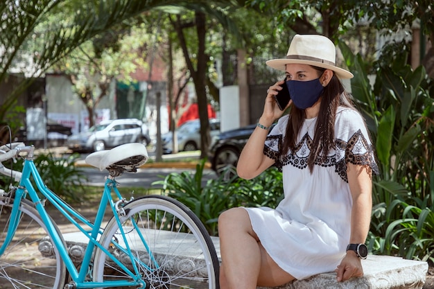 Donna con maschera che fa una telefonata nel parco