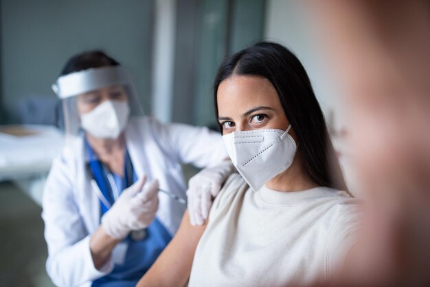Donna con maschera che si vaccina e si fa un selfie in ospedale sul coronavirus e il concetto di vaccinazione
