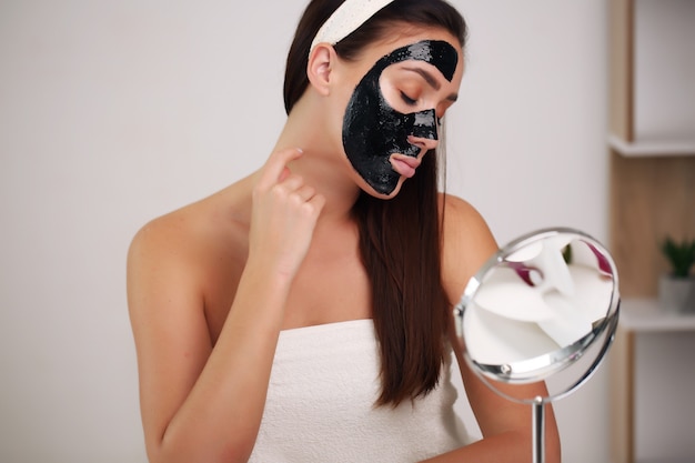 Donna con maschera nera detergente sul viso