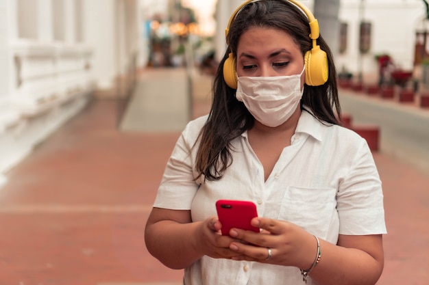 Donna con maschera protettiva in città che ascolta musica