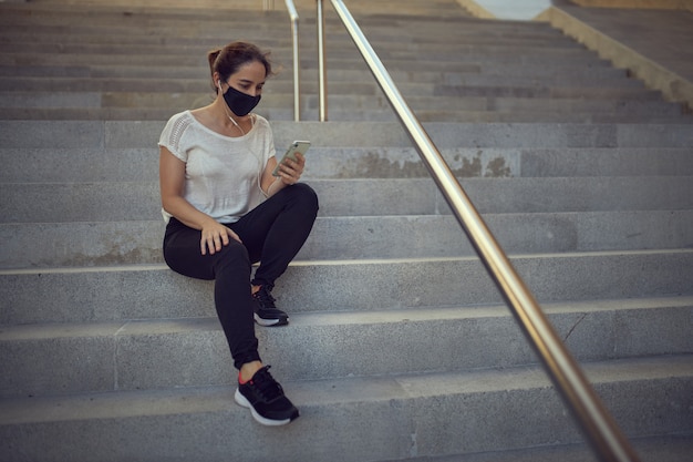 donna con maschera utilizzando il cellulare