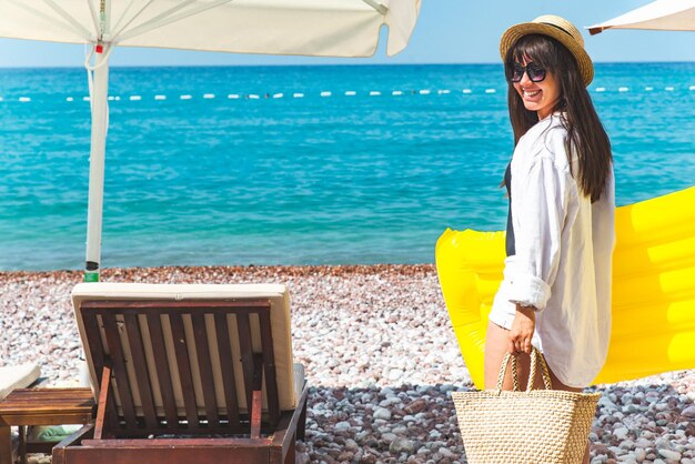 Donna con materasso gonfiabile giallo allo stile di vita dei lettini in riva al mare