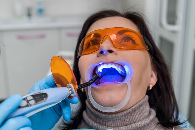 Donna con occhiali protettivi seduta sulla poltrona del dentista