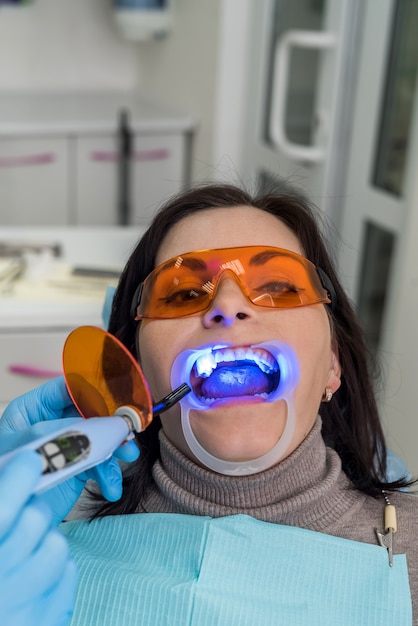 Donna con occhiali protettivi seduta sulla poltrona del dentista