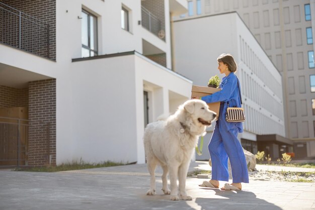 Donna con pacchi e cane cammina verso una casa