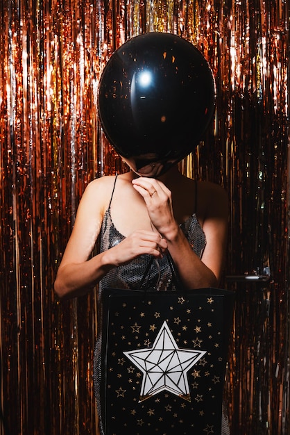 Donna con palloncino nero e pacchetto regalo sullo sfondo celebrativo Concetto di Black Friday