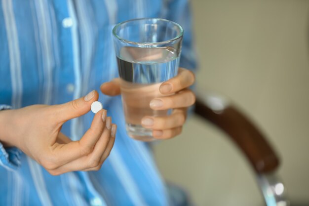 Donna con pillola e bicchiere d'acqua, primo piano