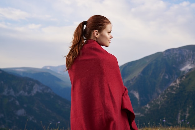 Donna con plaid rosso sulla natura in montagna vacanza avventura