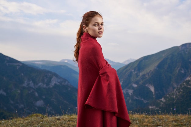 Donna con plaid rosso sulla natura in montagna vacanza avventura