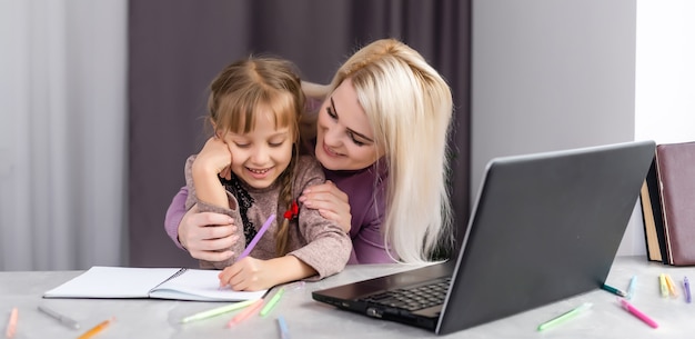 Donna con ragazza che fa i compiti sul computer portatile