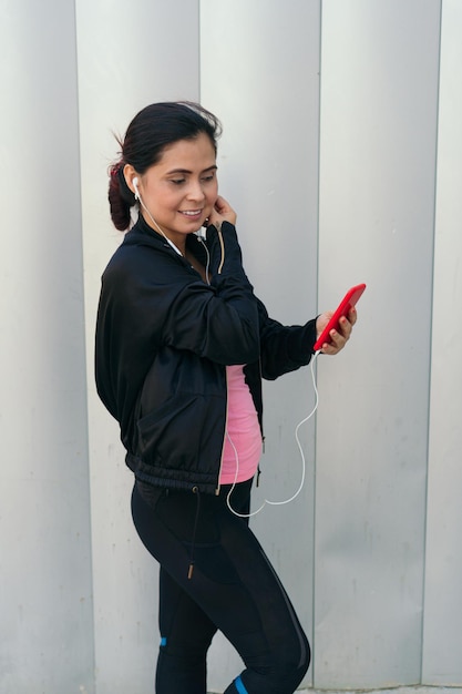 Donna con smartphone che indossa le cuffie e inizia ad ascoltare musica durante l'allenamento