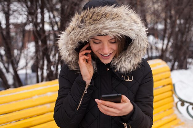 Donna con smartphone, chiamando. Stagione invernale.