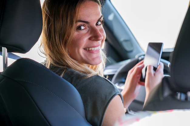 Donna con smartphone parcheggiato con la sua auto