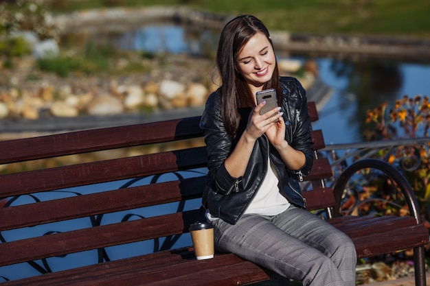 Donna con smartphone seduto nel parco