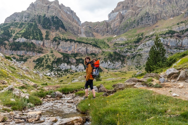 Donna con suo figlio nello zaino a piedi nei Pirenei in estate Valle de Tena Huesca