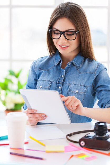 Donna con tavoletta digitale. Giovane donna allegra che lavora alla tavoletta digitale