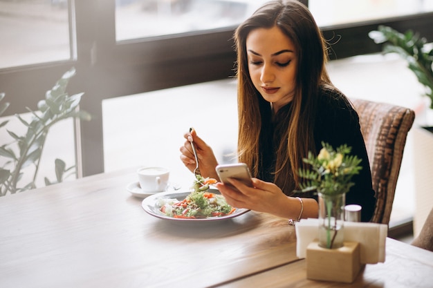 Donna con telefono caffè e insalata