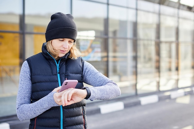 Donna con telefono cellulare collegato a un orologio intelligente