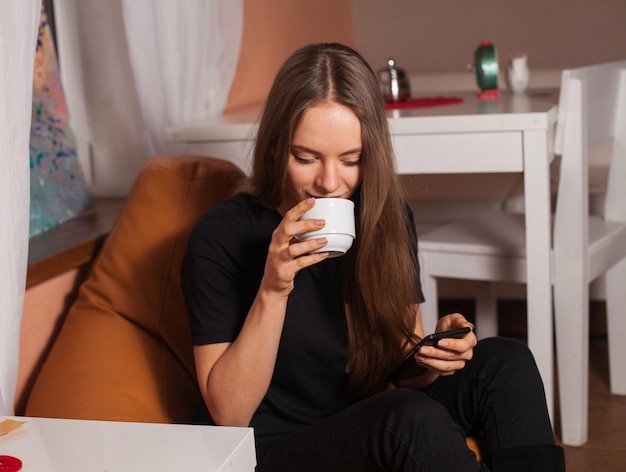 Donna con telefono cellulare e tazza di caffè