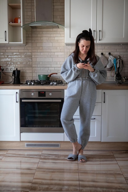 Donna con telefono in cucina