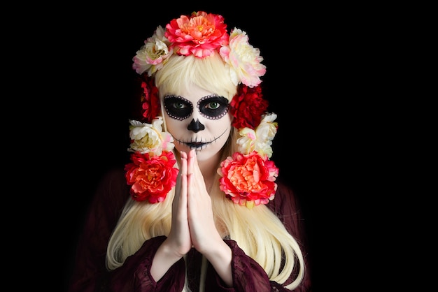 Donna con trucco del cranio dello zucchero e capelli biondi isolati su priorità bassa nera. Giorno della morte. Halloween.