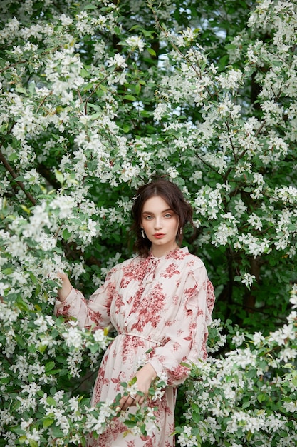 Donna con trucco naturale, cosmetici floreali per la pelle del viso, ragazza in posa su rami di fiori di melo in fiore in primavera