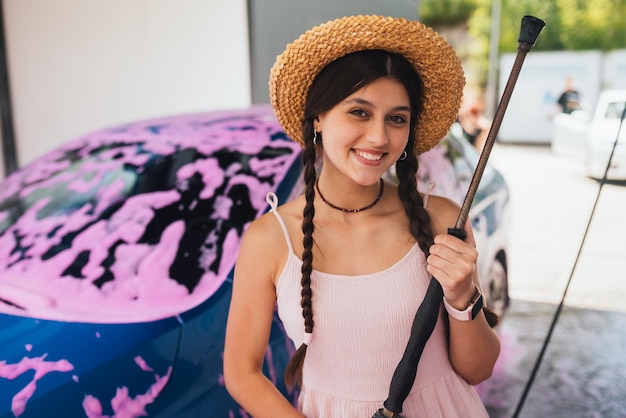 Donna con tubo flessibile in auto ricoperta di schiuma rosa