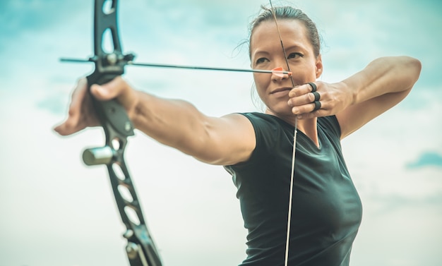 Donna con un arco all'aperto