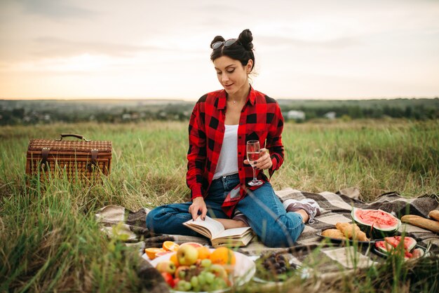 Donna con un bicchiere di vino, picnic sul prato