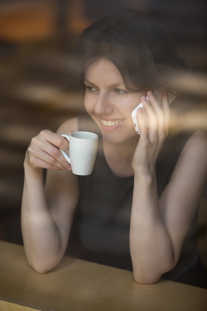 Donna con un caffè e parlare al telefono